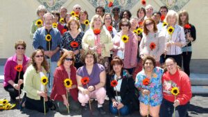 group of people holding sunflowers in from of a bulding