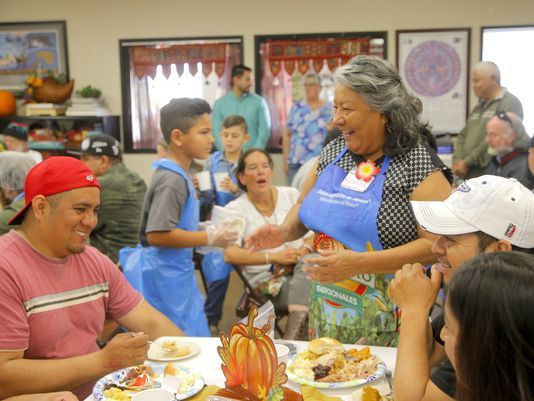 Salinas resource center staff, volunteers offer Thanksgiving friendship 13 a woman in a blue apron smiling at a group of people