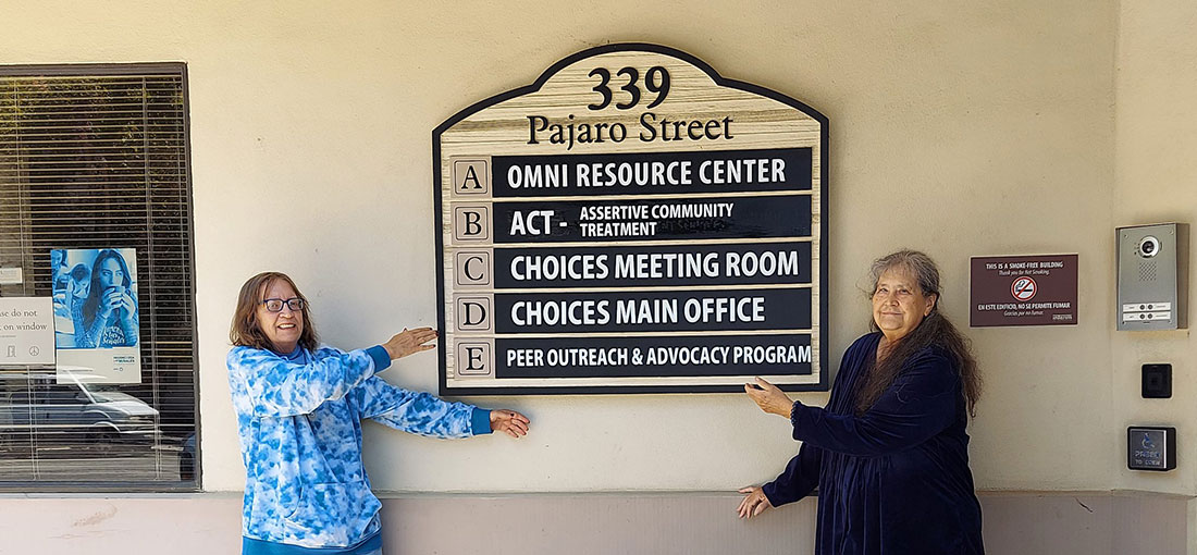 two women standing next to a sign