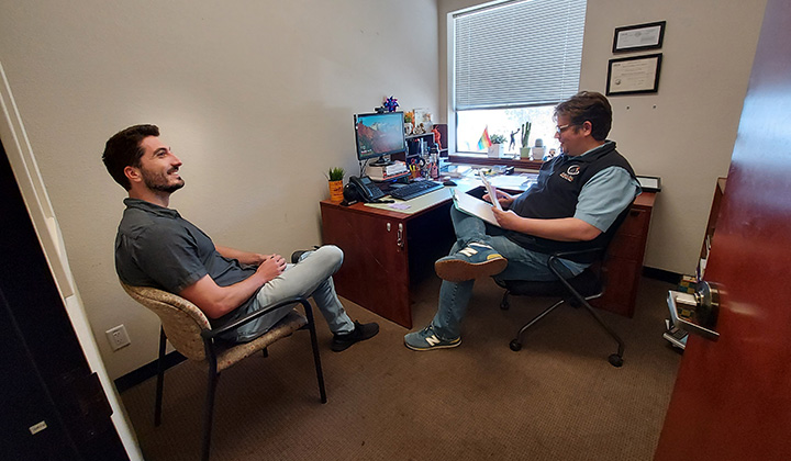 a man sitting in chairs and looking at another man