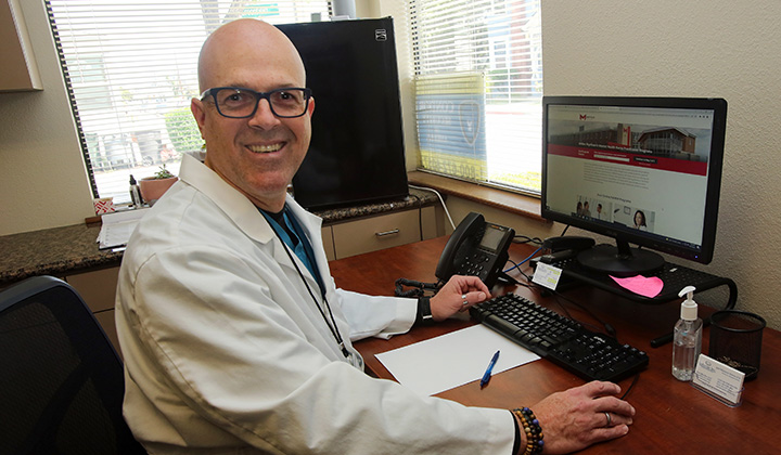 a man in a white coat sitting at a desk with a computer