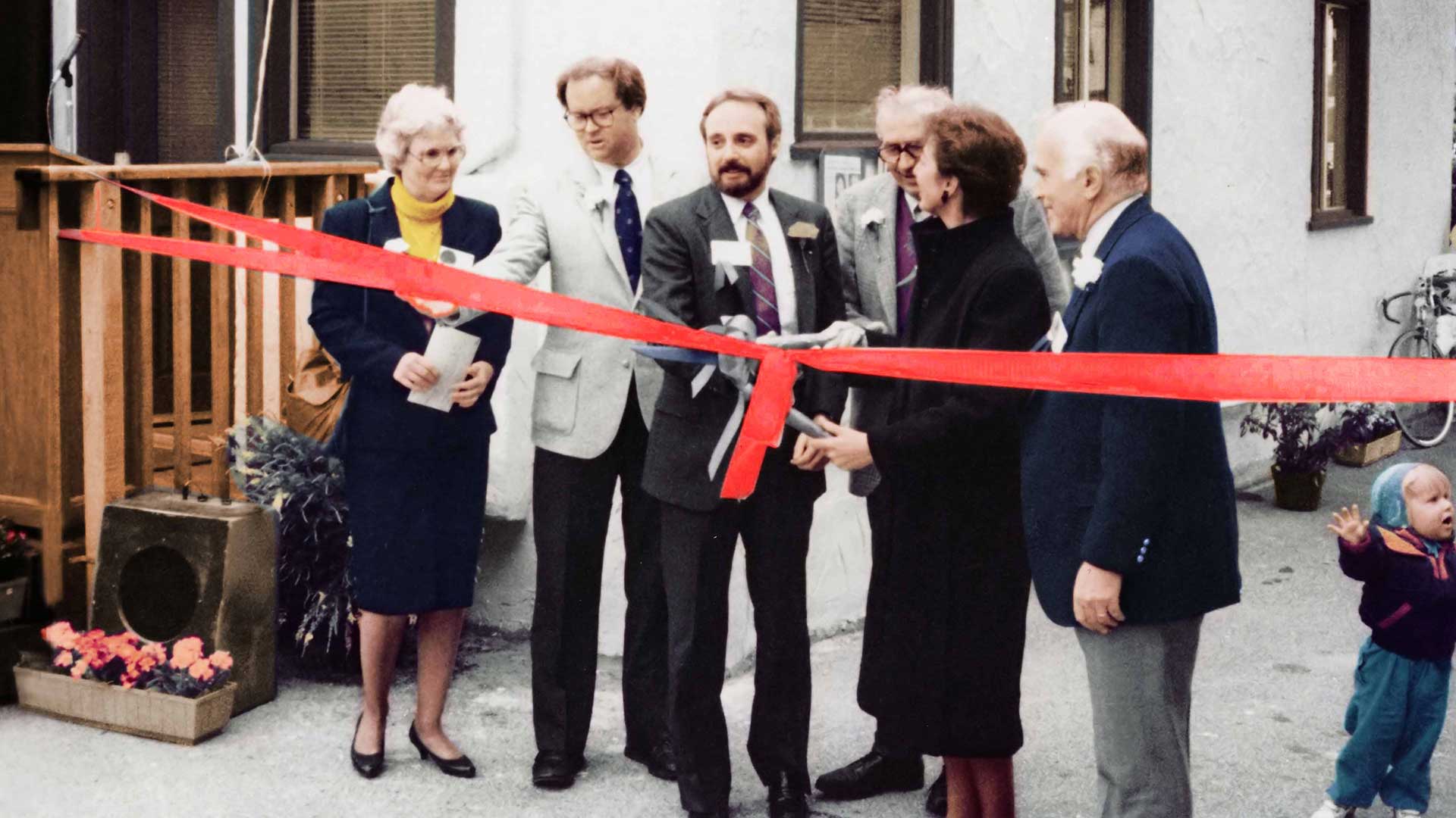 a group of people cutting a red ribbon