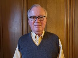 a man wearing glasses and a vest