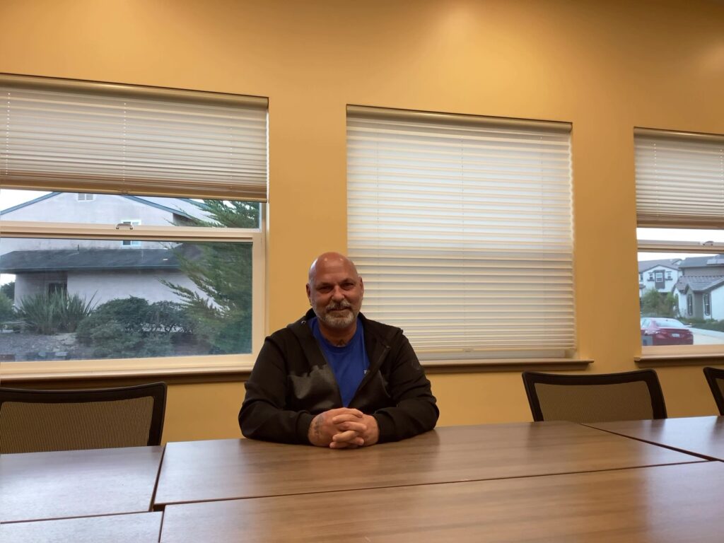 A Journey to Belonging: Building Recovery Through Community and Care 5 a man sitting at a table