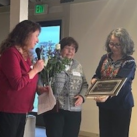 a group of women holding a microphone and a plaque
